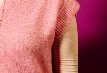 a woman wearing a pink sweater and a necklace