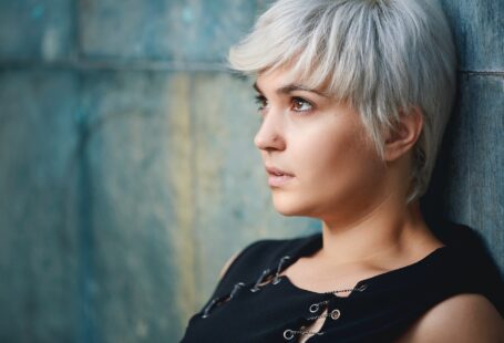 woman wearing black sleeveless top leaning on concrete wall